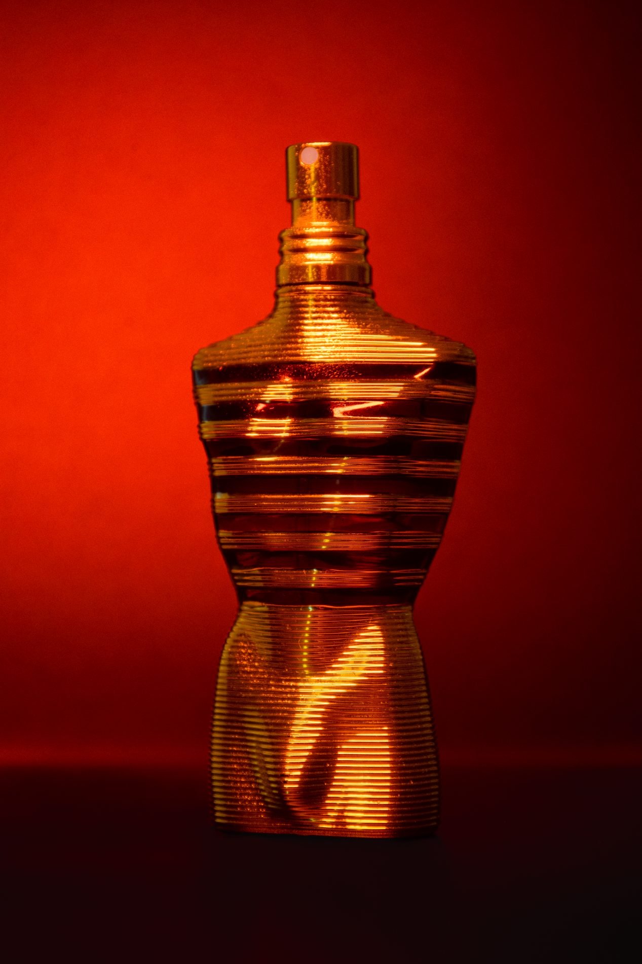 Frasco de perfume iluminado sobre fondo rojo